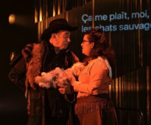 A cowboy talks to a waitress who's holding a toy cat.
