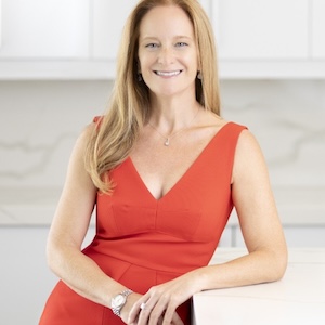 A woman in a red dress smiles at the camera.