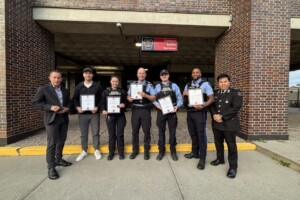 Campus Safety Services hold plaques in front of the Pigiarvik Building.