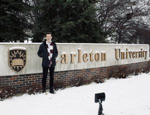 photo of Max outdoors in winter at Carleton sign