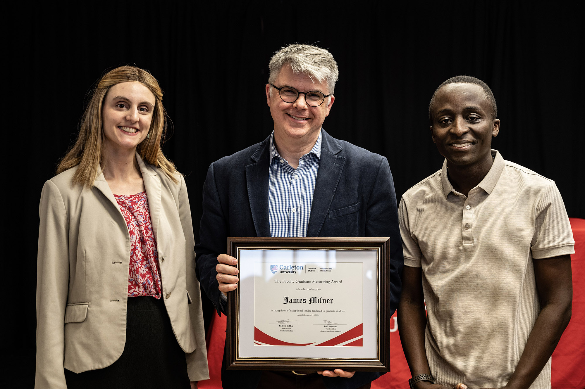 James holding award with current and former PhD students