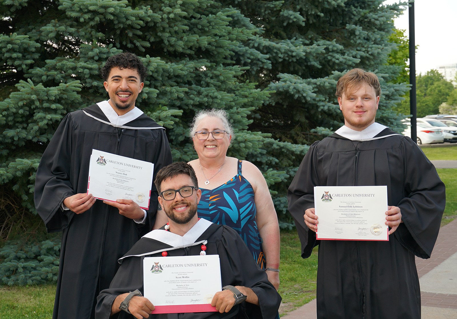 photo of three students in convocation robes with Undergraduate Supervisor