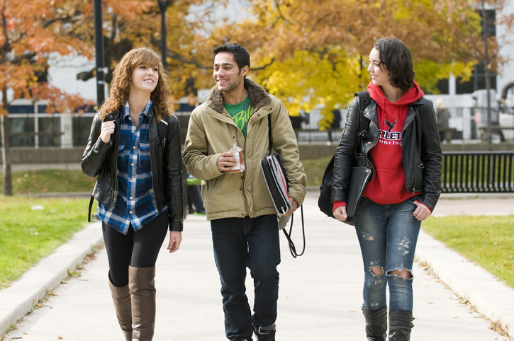 Students in jackets and fall clothing walk in the Tory quad on an autumn day.