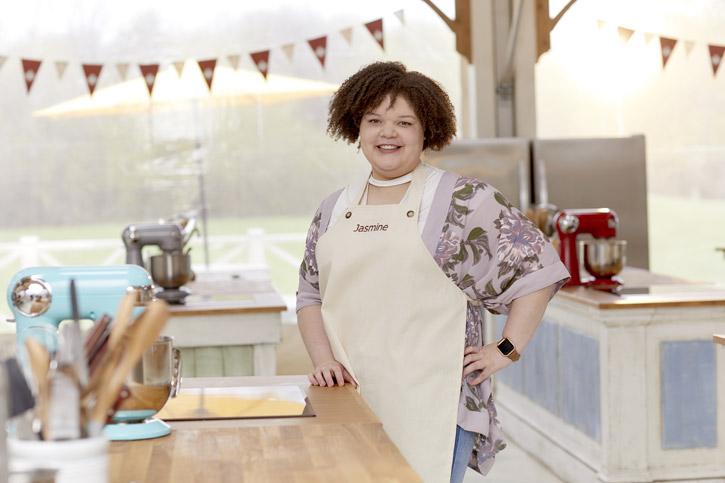 Jasmine Linton poses on the kitchen set of the Great Canadian Bake Off while wearing an apron