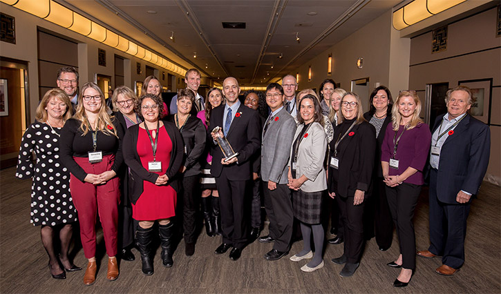 A large group of Carleton faculty and staff members stand together in a hallway during the Excellence Canada awards ceremony.