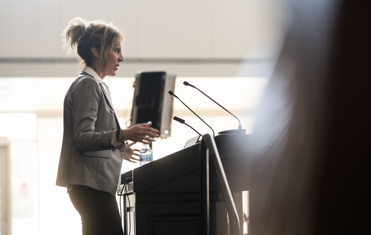 Prof. Joanna Pozzulo speaks at a podium on Psychology Mental Health Day
