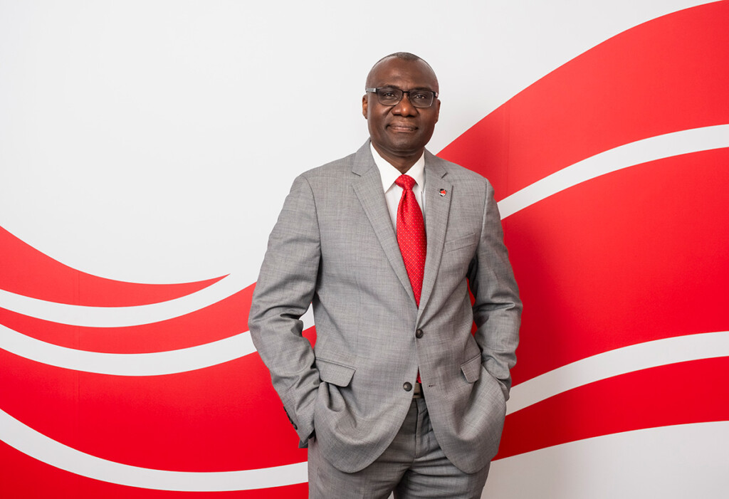 A man wearing a suit poses for a professional photo with his hands in his pockets.