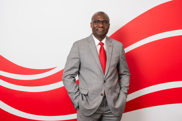 A man wearing a suit poses for a professional photo with his hands in his pockets.
