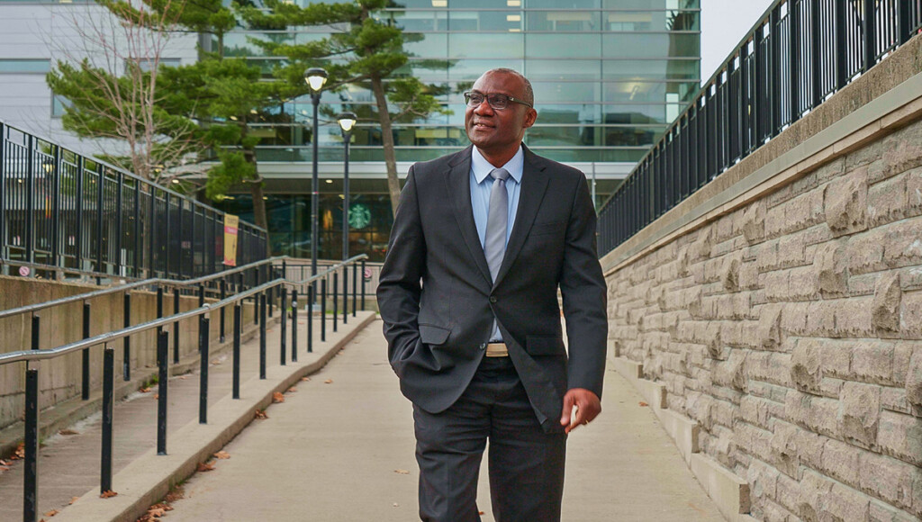 A man wearing a suit walks down a brick path.