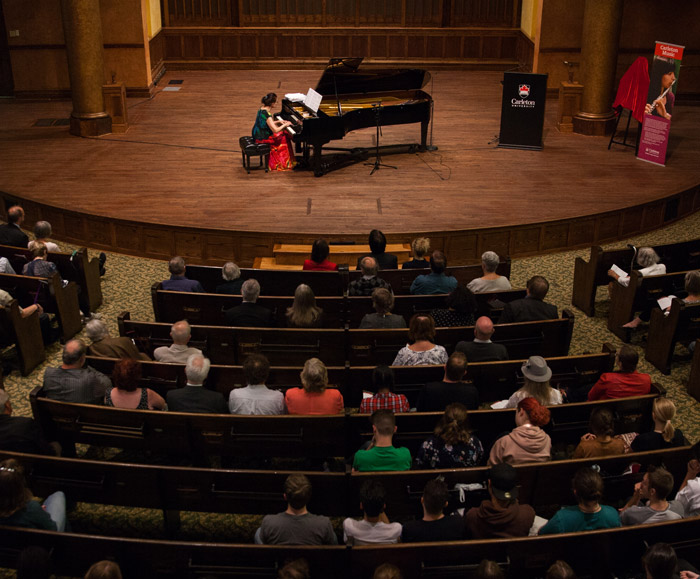 Elaine Keillor plays piano onstage at the Carleton Dominion-Chalmers Centre as a crowd watches