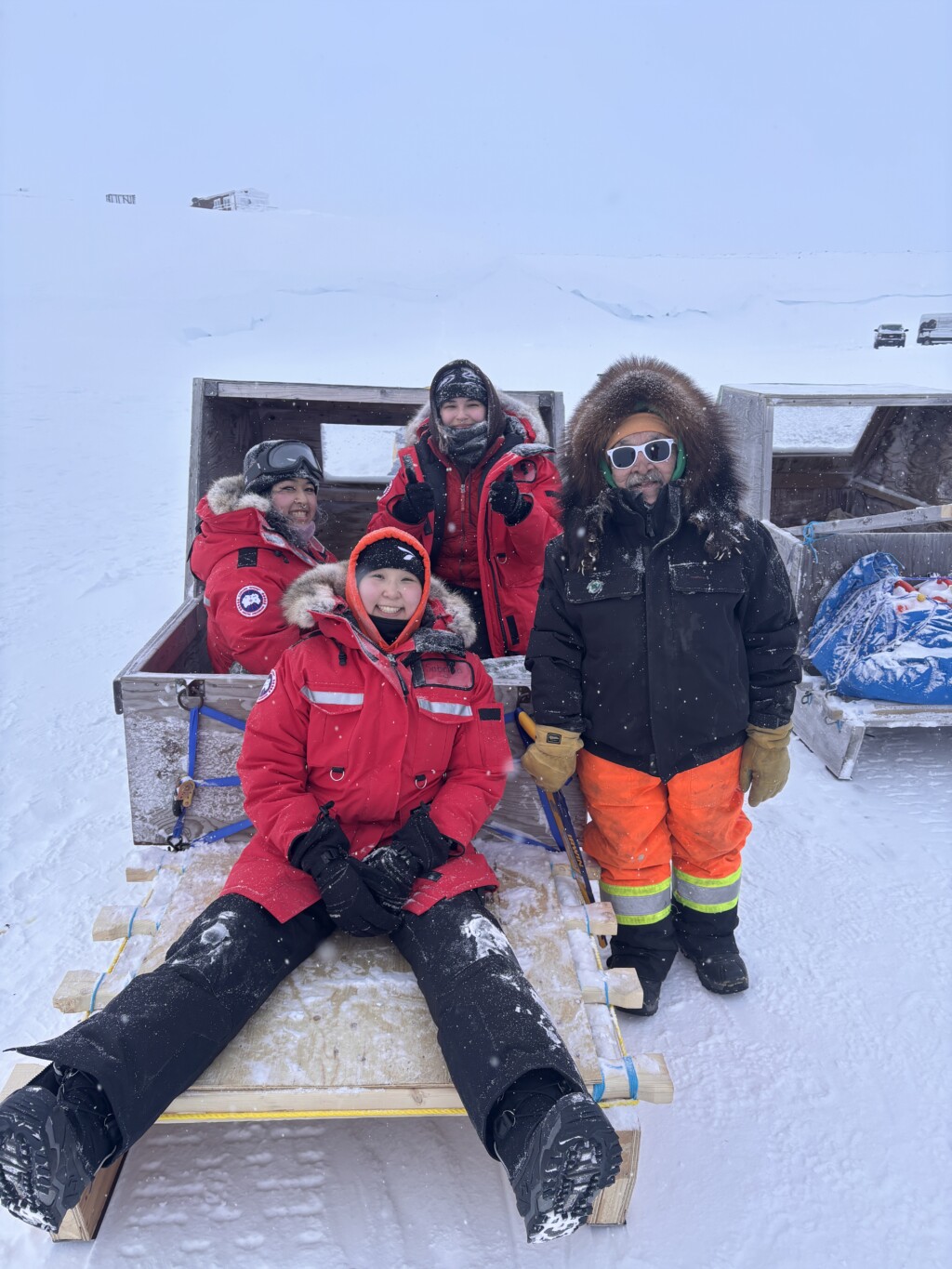 Group of students sitting and leaning on snow machines
