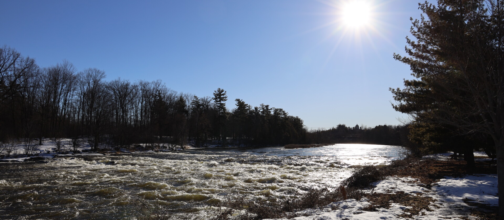Blue sky, rushing water and trees. 