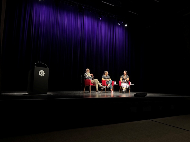 Panel of three people sitting on stage.
