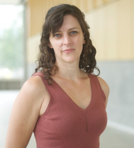 Woman standing with Long wavy black hair and rose tank top. 