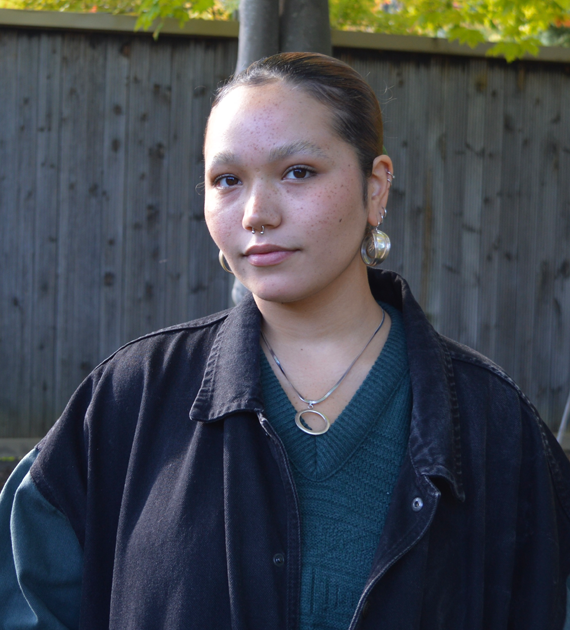 Felicity Hauwert, brown hair in a ponytail, large earrings and a nose ring.