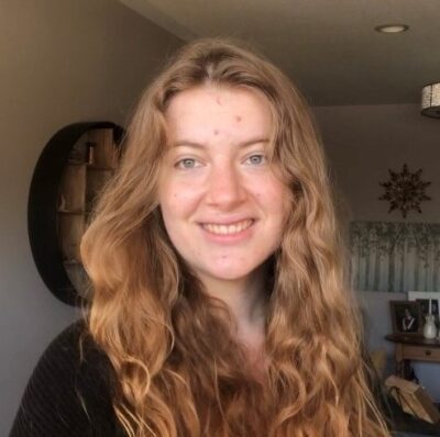 Olivia Little - Smiling w
omen with red long hair and black top. 