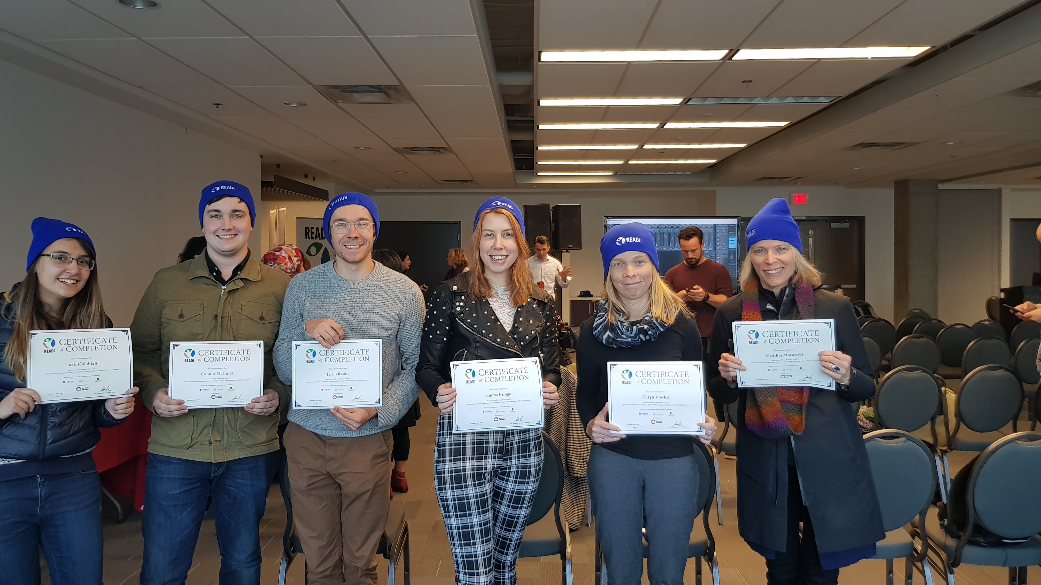 Six students pose, holding their READi certificates and wearing blue READi bieanies.