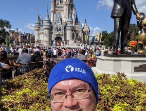 Adrian is looking at the camera, wearing a blue tuque with the READi logo, in front of the Disney Cinderella Castle