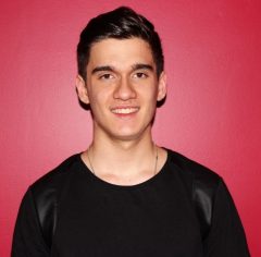 Adrian smiling in front of a red background.