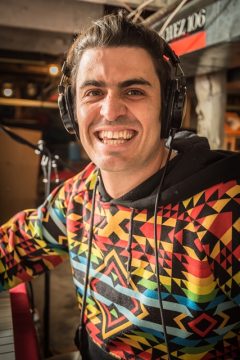 Jack is smiling at the camera while wearing a brightly patterned sweater and headphones