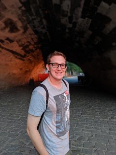 Max Polzin is turning to face the camera, smiling in front of a tunnel