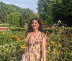 Pallavi is outside in a flower garden, looking at the camera