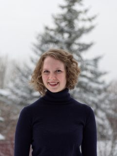 Samantha Schneider standing outside in front of a snow-covered tree