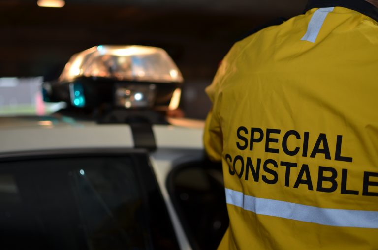 Emergency lights on a vehicle and a Special Constable wearing a yellow jacket.