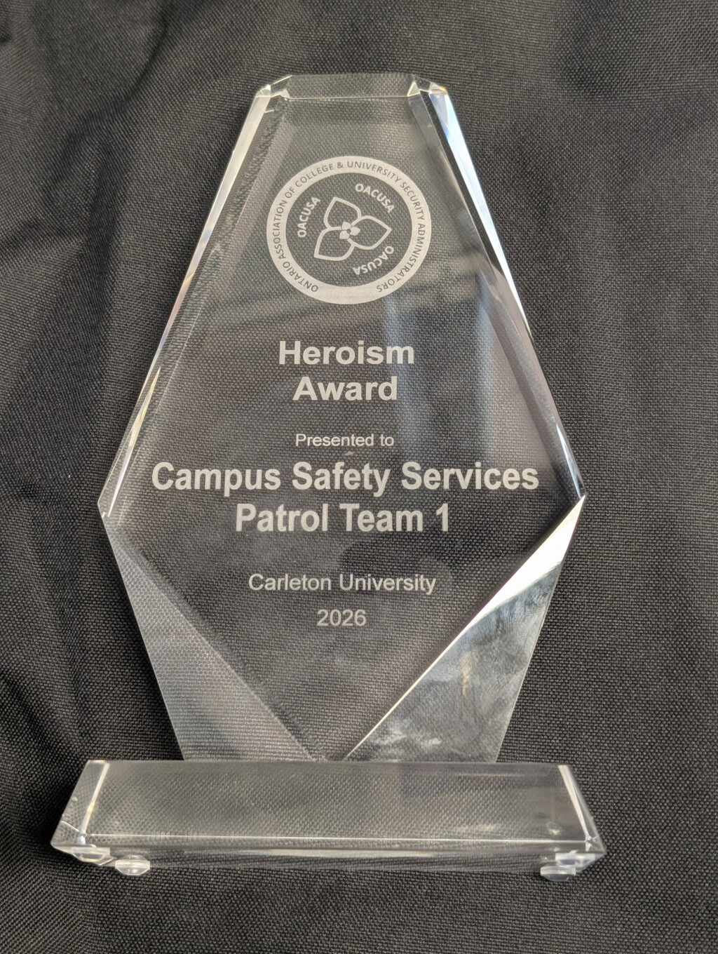 Glass trophy with writing. OACUSA Heroism Award