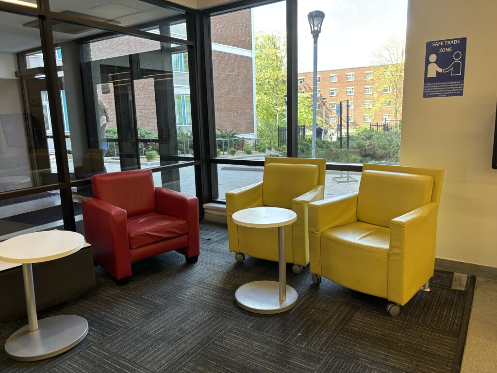 Picture of the Seating area in Teraanga Commons. 3 chairs and 2 little tables. Safe Trade Zone sign on the wall.