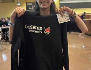 Student displaying their bingo prize: Carleton sweater.