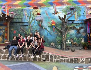 Group of students photographed in front of mural in Guatemala.