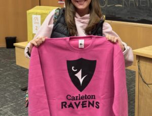 Student displaying their raffle prize: Pink Ravens sweater.