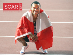Andre De Grasse wearing Canada Flag over his shoulders while posing on the track.