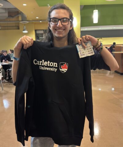 Student displaying their bingo prize: Carleton sweater.