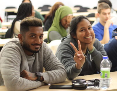 Students working as a group at their desks. One student showing the peace sign.