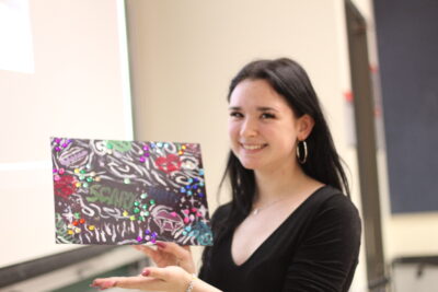 A student displaying their completed paint canvas.