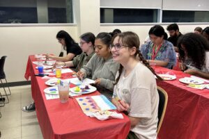 Students sitting in a row and working on their canvases.