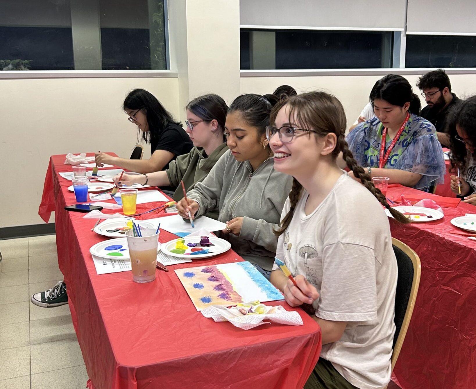 Students sitting in a row and working on their canvases.