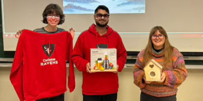 Three students displaying their raffle prizes that were won at the end of the event.