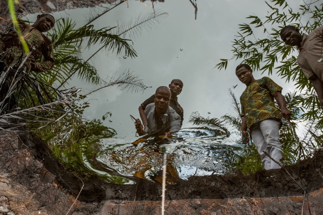 Kegbara Dere community leader Sonny Olulu probes an oil containment pond outside his home in the Niger Delta region of Nigeria.