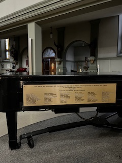 a photo of a grand piano with a gold plaque on its side