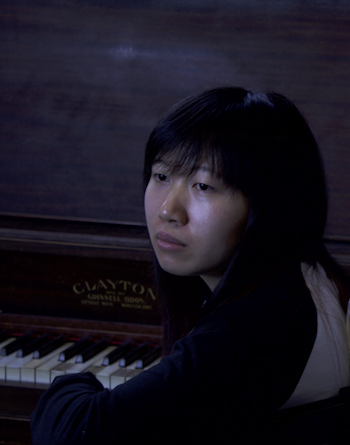 Alcina seated at a piano