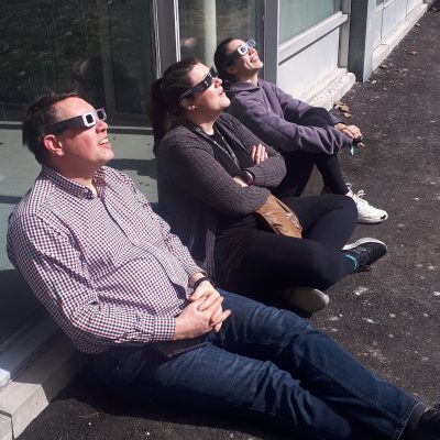Michael Rodgers, Laura Barrow, and Alex Ethier stare at the solar eclipse on April 8, 2024
