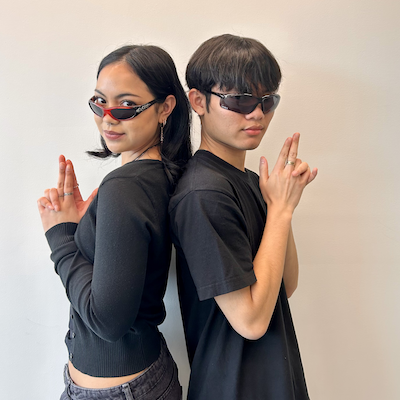 Keisha and Vihop pose back to back with their fingers intertwined pistol-style.