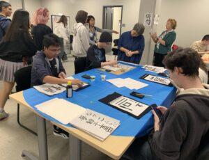 Students sitting at tables working on their calligraphy.