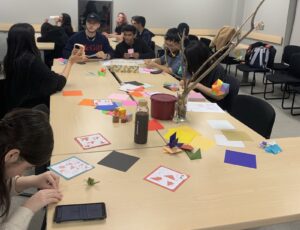 Students sitting at tables working on their origami.