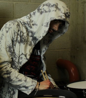 SETH with drum sticks in hand hunches over a snare drum