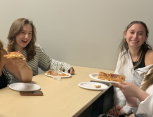 Group of students enjoying pizza at a table.