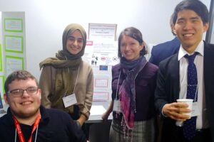 Four students in front of their poster